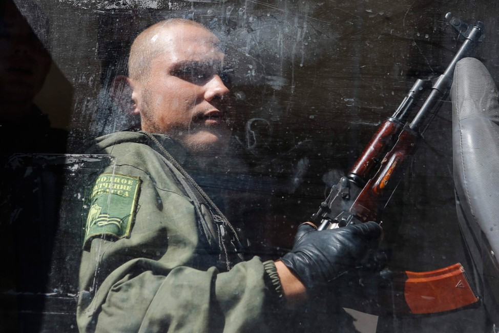 An armed pro-Russian separatist sits in a bus after a rally in Donetsk