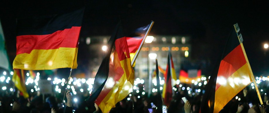 Participants hold up their mobile phones and wave German national flags during a demonstration called by anti-immigration group PEGIDA in Dresden