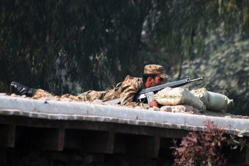 A Pakistani soldier takes up a position above a road near a military run school that is under attack by Taliban gunmen in Peshawar
