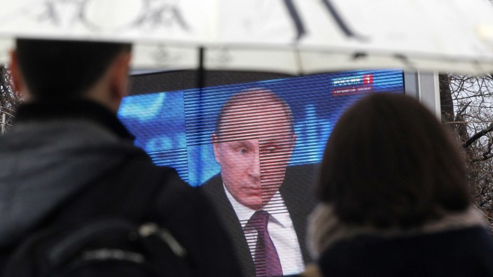Russland unter Putin: Ein Paar verfolgt in der Krimstadt Sewastopol auf einer Leinwand die Ansprache des russischen Präsidenten Wladimir Putin.