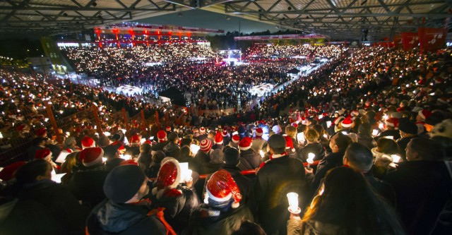 People attend the 'Weihnachtssingen' a candle-lit carol concertat the Alte Foersterei stadium in Berlin