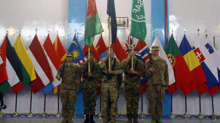 Afghan and NATO-led ISAF soldiers stand at attention during the change of mission ceremony in Kabul