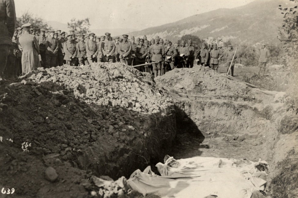 Austro-Hungarian soldiers stand in front of a mass grave on the Eastern Front in this 1915 handout picture