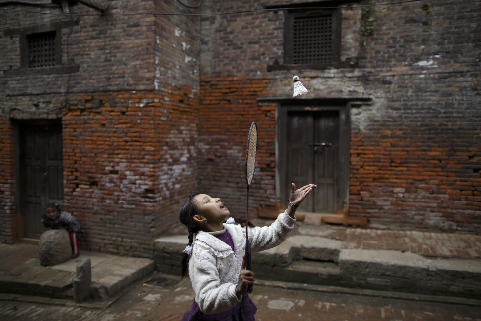 A girl plays badminton along the street outside the old houses of the ancient city of Bhaktapur