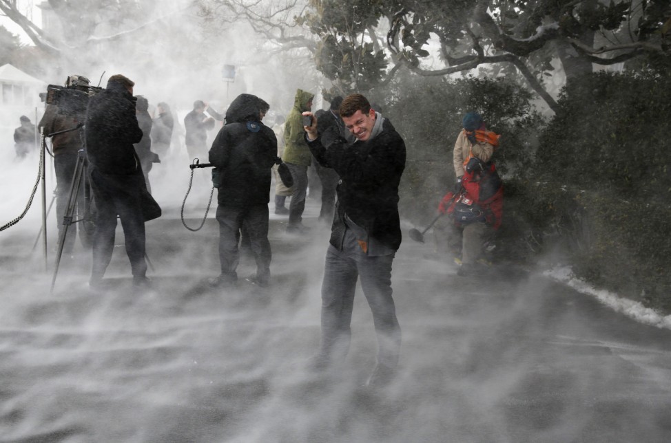 Members of the press, including NBC's Dixon, face the blowing snow caused by Marine One as it landed on the South Lawn before picking up U.S. President Barack Obama at the White House in Washington