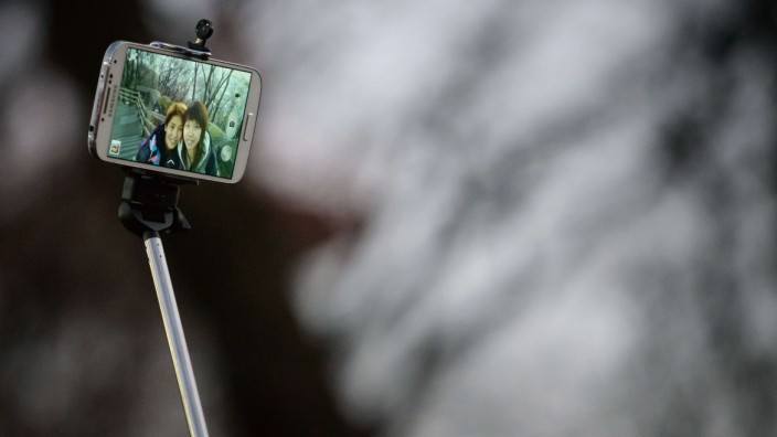 Smart Home: Menschen fotografieren sich per Selfie-Stick. Der Auslöser im Stab arbeitet mit Bluetooth.