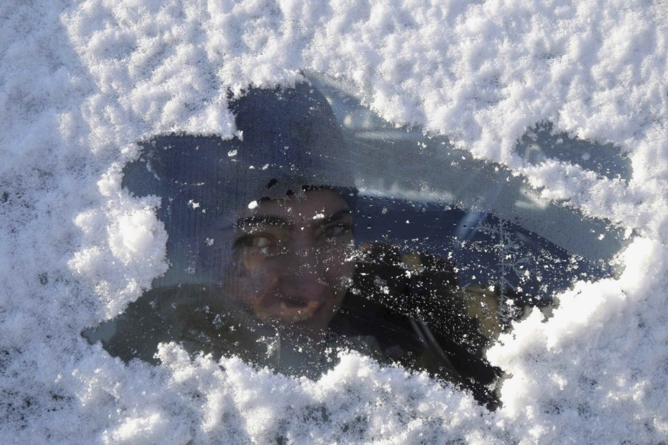A woman sits in a car covered with snow in Houla village, southern Lebanon