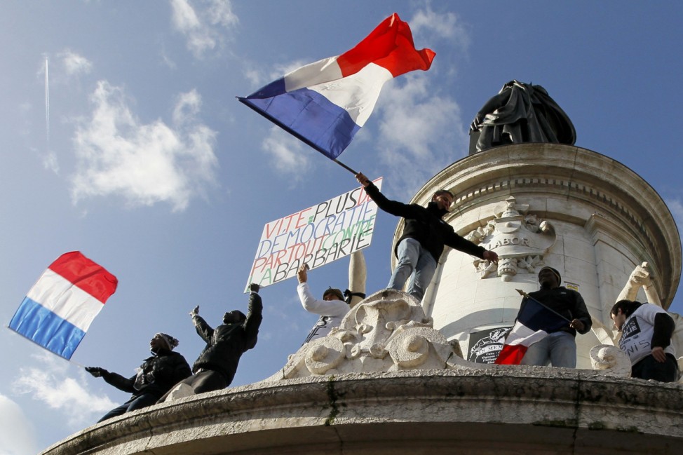 People holding a poster reading 'Quick more democracy everywhere against barbarism' take part in a solidarity march (Marche Republicaine) in the streets of Paris