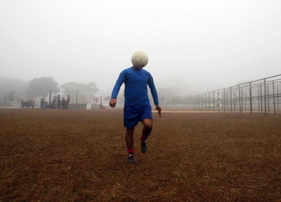A man controls a ball during his soccer practice in a public park on a foggy morning in Agartala