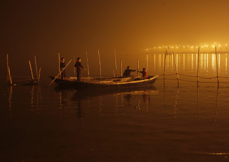 Boys tie their boats as fog covers the banks of the Yamuna river on a cold evening in the northern Indian city of Allahabad