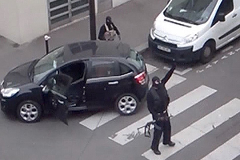 Gunmen gesture as they return to their car after the attack outside the offices of French satirical weekly newspaper Charlie Hebdo