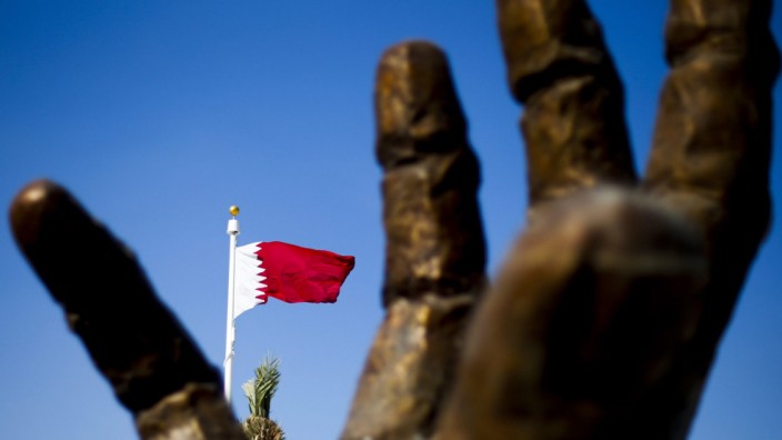 Die Nationalflagge von Katar hinter einer Skulptur in Doha