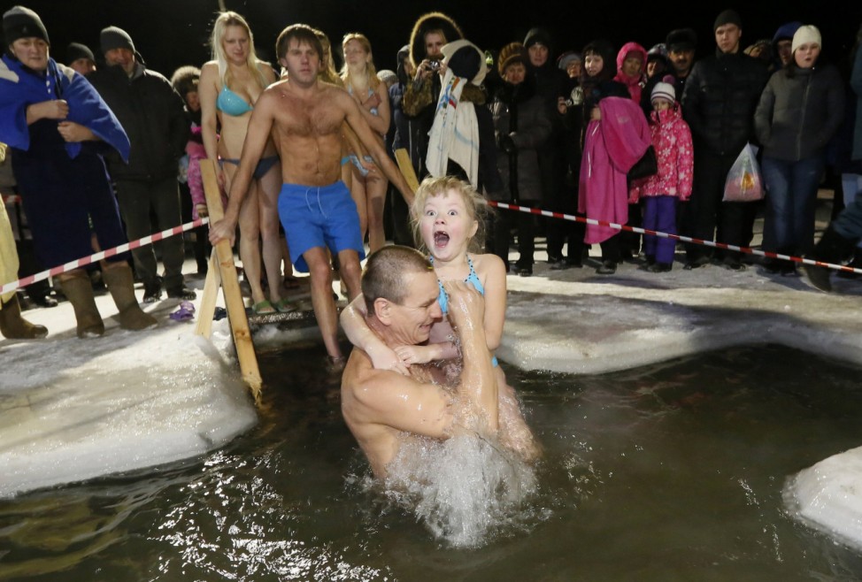 A man and his daughter immerse themselves in an ice hole in the Chulym river, during celebrations for Russian Orthodox Epiphany outside of Nazarovo, Krasnoyarsk region