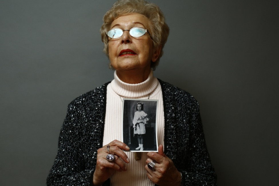 Auschwitz death camp survivor Janina Reklajtis holds a photo of herself taken during the war as she poses for a portrait in Warsaw