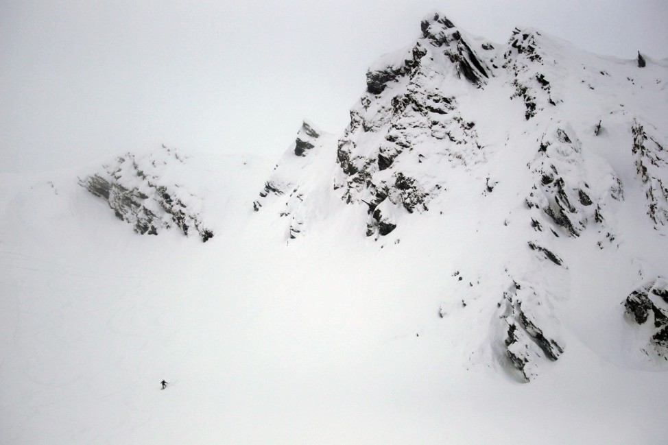 A snowboarder descends from a rough mountain slope towards Balea glaciar lake at Balea Lac resort in the Fagaras mountains
