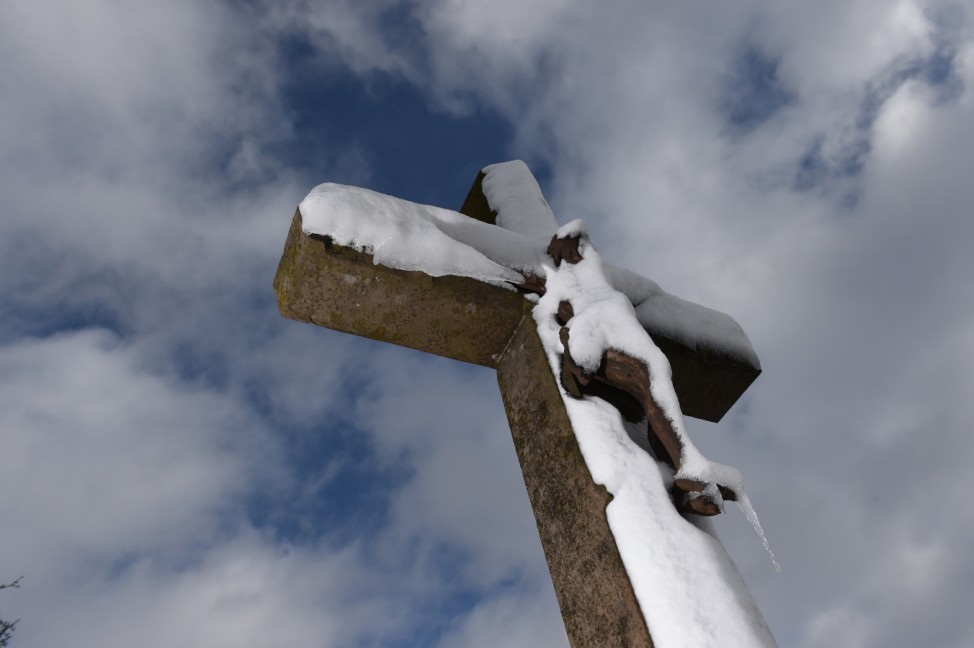 Neuer Schnee bedeckt altes Kreuz