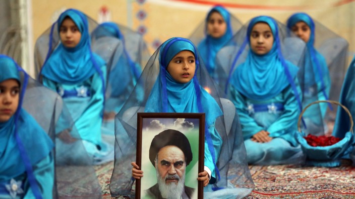 Hidschab-Pflicht in Iran: Junge iranische Mädchen mit einem Porträt von Ayatollah Ruhollah Khomeini.