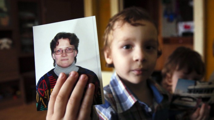 Artur, son of Russian activist Davydova and her husband Gorlov, holds up a photo of his mother to the camera, at their home in Vyazma