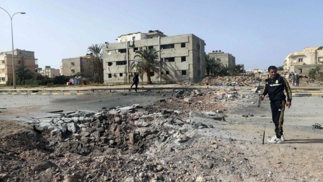 People stand near the site of an explosion in Benghazi