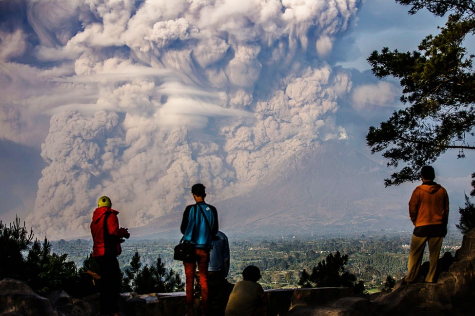 People watch as Mt. Sinabung ejects ash into the air during an eruption in Karo regency, Indonesia's North Sumatra province