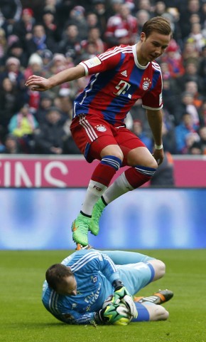 Bayern Munich's Goetze jumps over goalkeeper Drobny of Hamburger SV during German Bundesliga soccer match in Munich