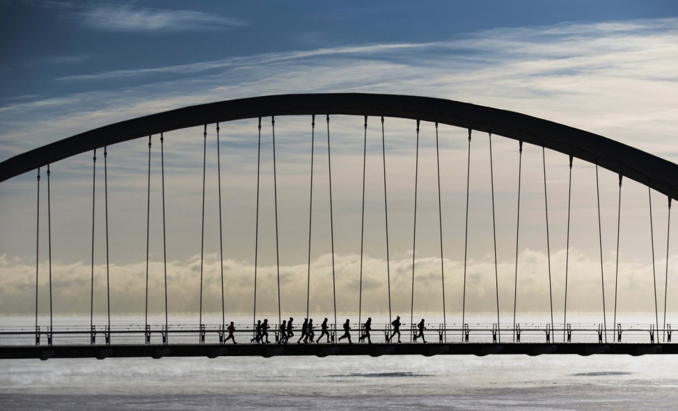 Group of joggers run across the Humber Bay Arch Bridge during extreme cold temperatures in Toronto