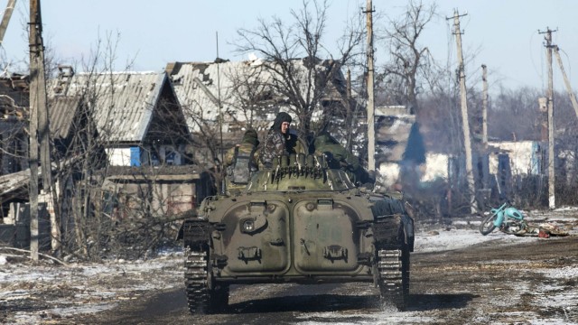 Fighters with separatist self-proclaimed Donetsk People's Republic army ride atop moving armoured personnel carrier in village of Nikishine
