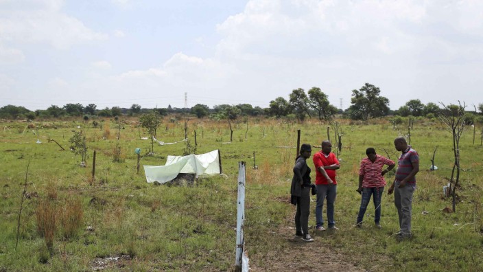 Residents stand in front of markings with sticks at an open land area in Nellmapius township, east of Pretoria