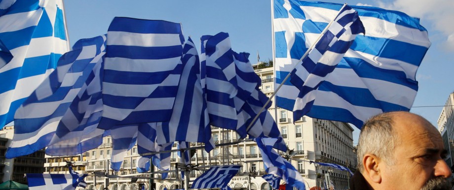 Greek national flags displayed for sale flutter during an anti-austerity pro-government demonstration in front of the parliament in Athens