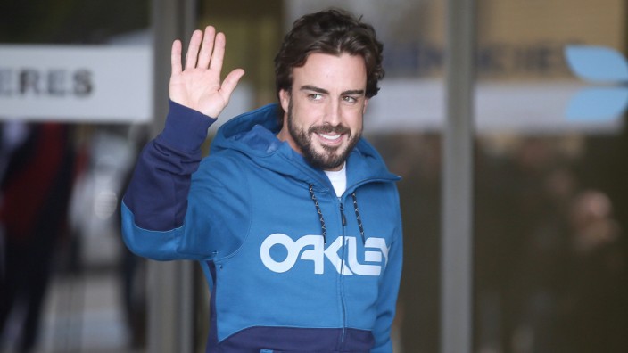McLaren's Formula One driver Alonso of Spain gestures to the media as he leaves a hospital where he has been hospitalized since Sunday, in Sant Cugat