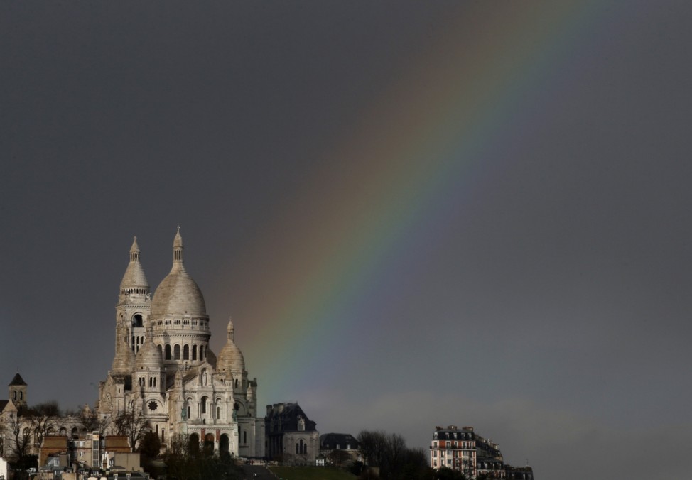 A rainbow is seen against rain clouds above the Sacre Coeur Basilica on Montmartre after a sudden rain shower hit Paris