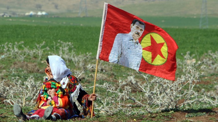 A Turkish Kurdish woman with a child sits next to a PKK flag with a picture of the imprisoned Kurdish rebel leader Abdullah Ocalan during a women's day event in Silopi, Kurdish dominated southeastern Turkey