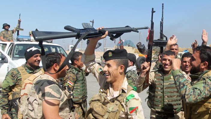 Iraqi soldiers raise their weapons as they cheer on the outskirts of the city of Tikrit as they prepare to launch a military operation to take control of the city from Islamic State (IS) group jihadis