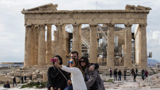 Tourists take a selfie photograph of themselves in front of the Parthenon Temple, at the archaeological site of the Acropolis Hill in Athens