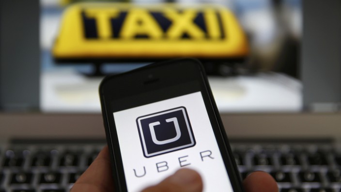 File illustration picture shows the logo of car-sharing service app Uber on a smartphone next to the picture of an official German taxi sign