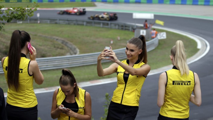Pirelli hostesses use mobile devices as drivers compete during the Hungarian F1 Grand Prix at the Hungaroring circuit, near Budapest