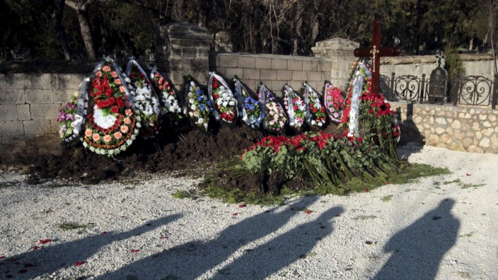 Shadows of people are seen near an unnamed grave, believed to be that of ousted Ukrainian president Viktor Yanukovich's son Viktor, at the Brotherhood cemetery in Sevastopol