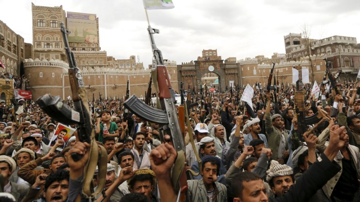 Shi'ite Muslim rebels hold up their weapons during a rally against air strikes in Sanaa