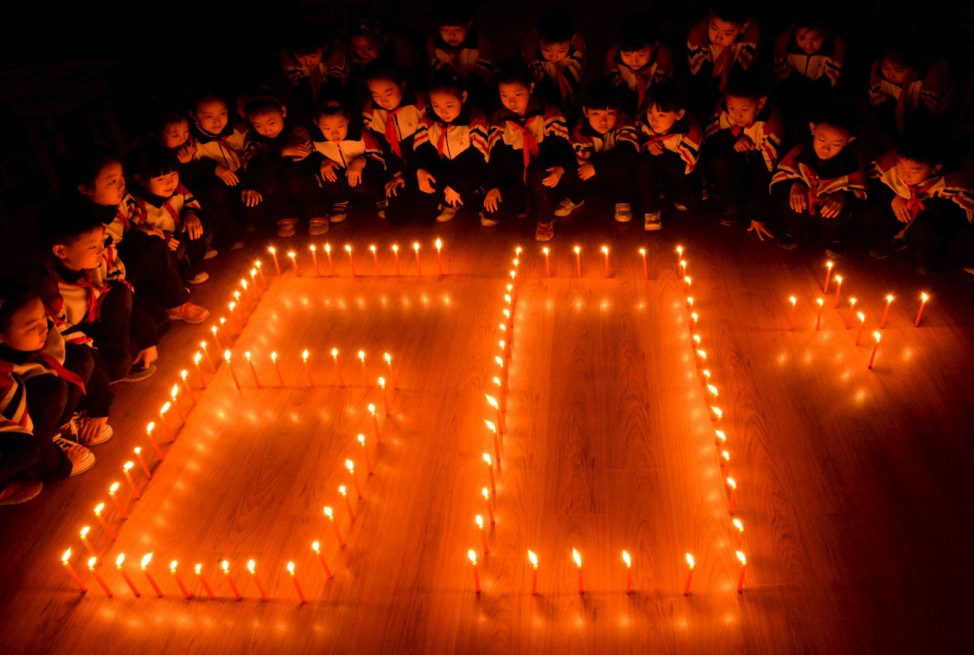 Students place candles in shape of the logo of Earth Hour, at a primary school in Handan