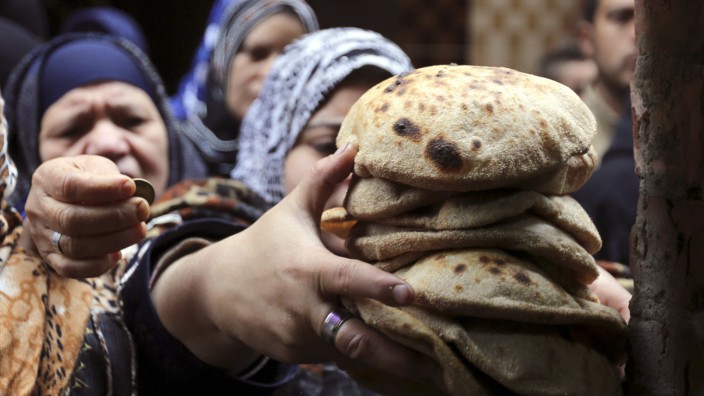A woman buys bread at a bakery in Cairo
