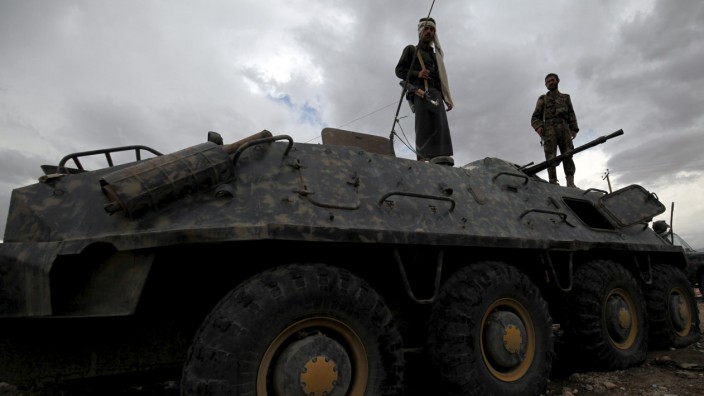 Plain-clothes policemen stand on top of a police vehicle at a checkpoint in Sanaa