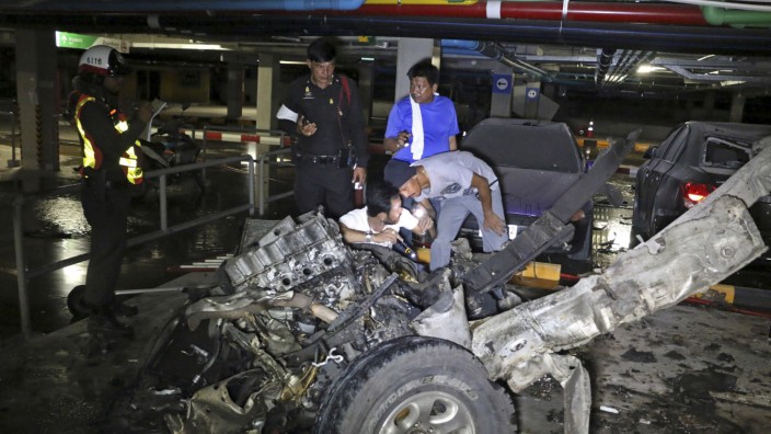 Police officers inspect the site of a car bomb blast at a car park of a shopping mall in Koh Samui