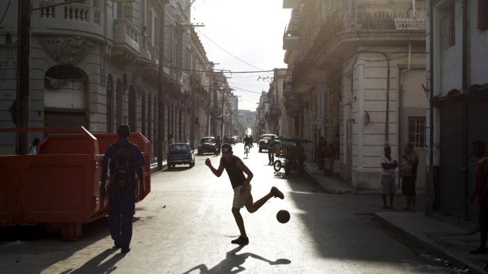 A young man plays soccer on a street in Havana