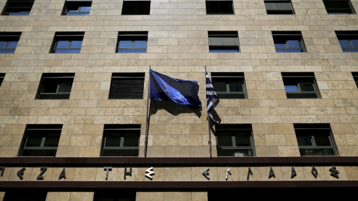 An EU flag flutters next to a Greek flag on the facade of the Bank of Greece headquarters in Athens