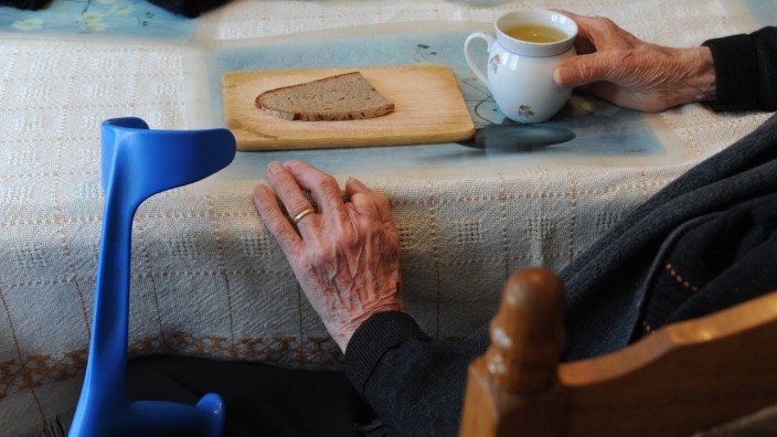 Alte Hände mit Teetasse und Brotscheibe, 2010