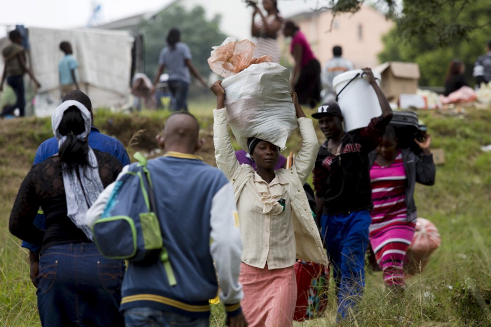 Foreigners from Zimbabwe carry their bags before boarding a bus home, from a camp for those affected by anti-immigrant violence in Chatsworth, north of Durban