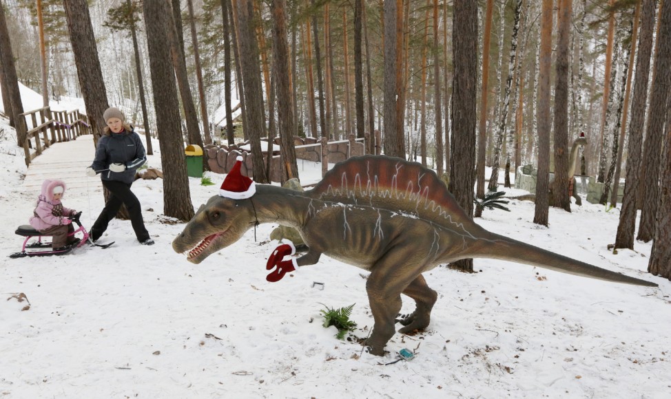 People walk past a model of a dinosaur at the 'Dinosaurs Park' at the Royev Ruchey zoo in Krasnoyarsk; Dinosaurs
