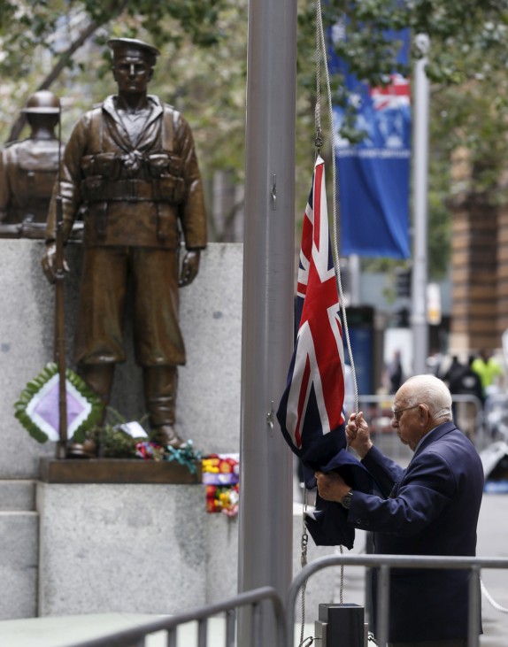 Chief Cenotaph Attendant Wal Scott-Smith raises the Australian flag alongside the Cenotaph War Memorial in Sydney on the eve of ANZAC day