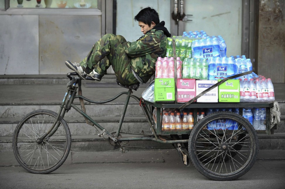 A beverage delivery man takes a nap on a tricycle in Shenyang
