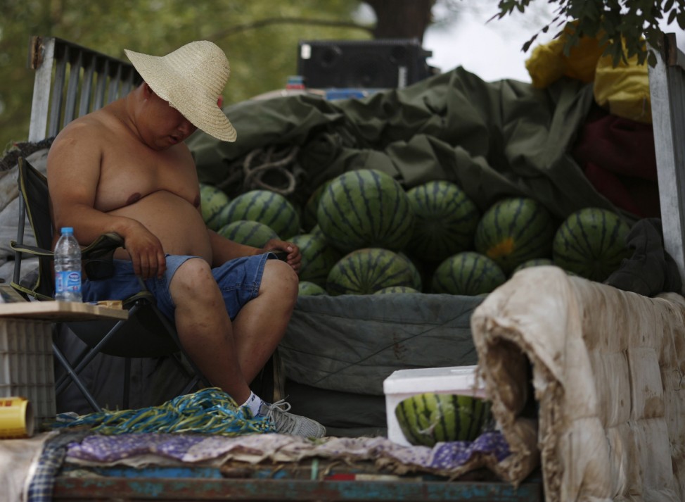 A watermelon vendor takes a nap while waiting for customers during a hot day in Beijing